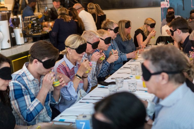 Brunch attendees blindfolded and drinking fruit drink