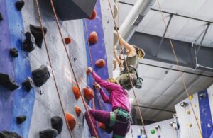 Kara and another climber are lead climbing in a rock climbing gym.