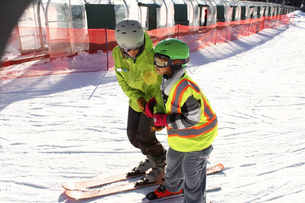 A guide is helping a young boy go skiing.