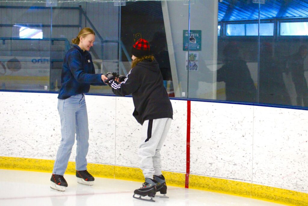 A woman guide is helping a student go ice-skating.