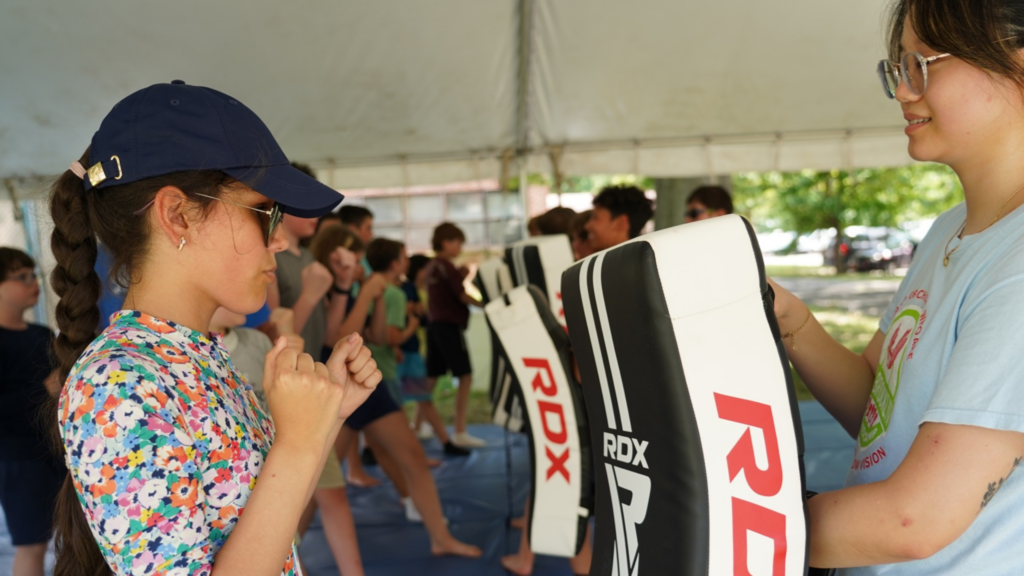 In this photo, a girl is learning to spar with a punching bag.