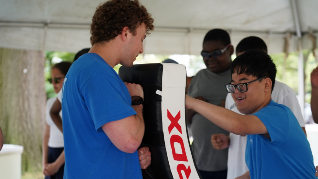 In this photo, a little boy is hitting a punching bag.