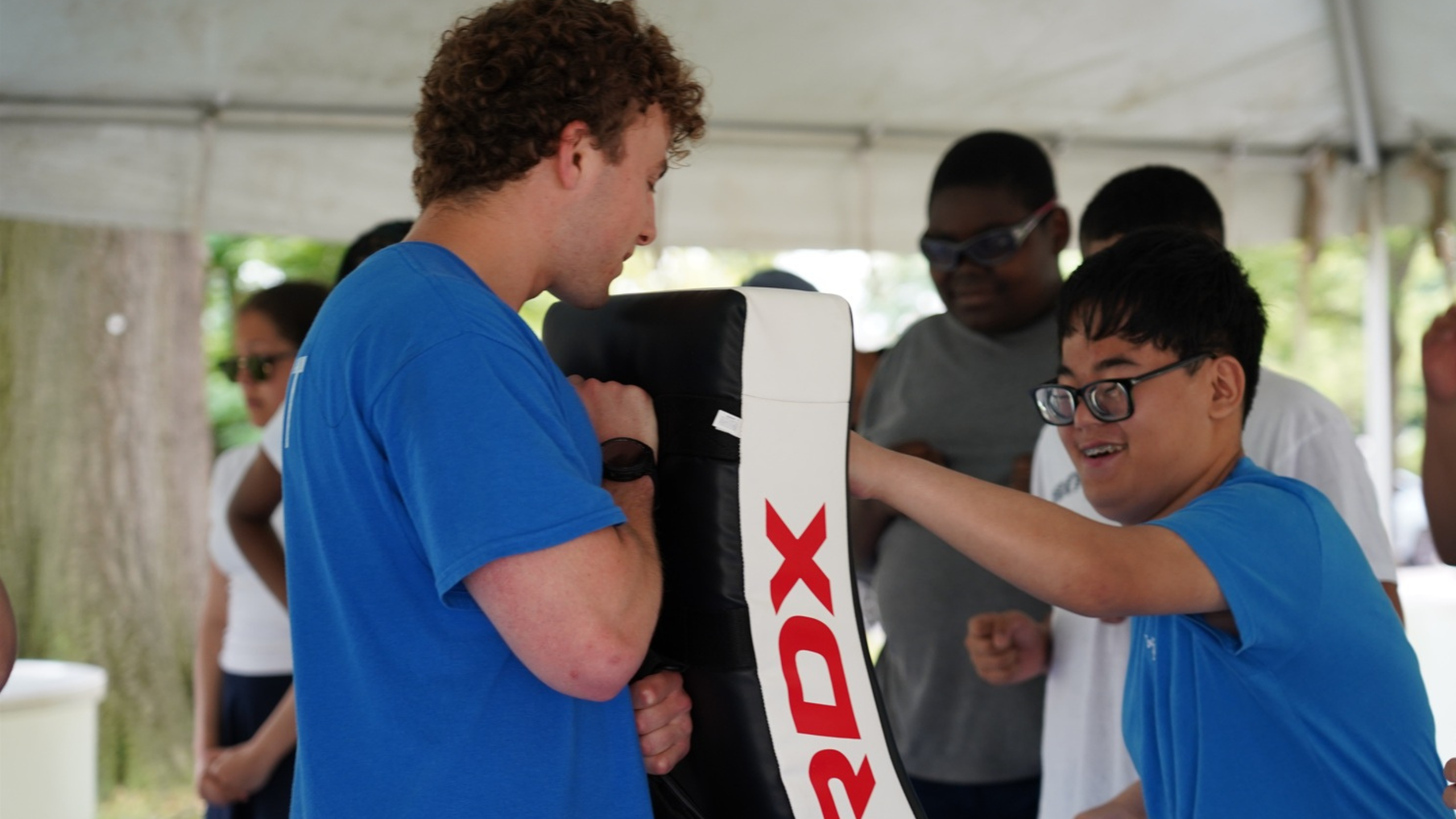 In this photo, a little boy is hitting a punching bag.