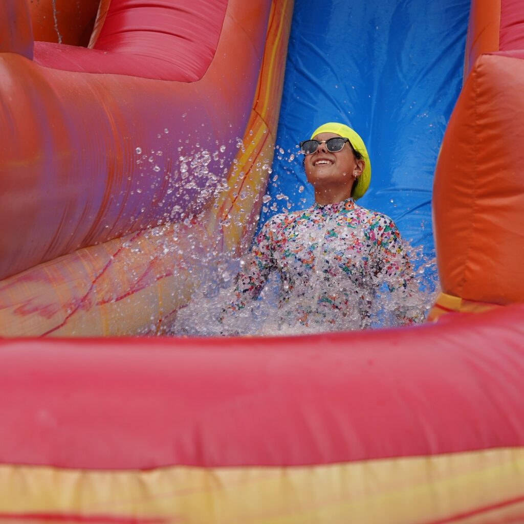 A young girl is sliding down a blowup slide into a water splash zone. 